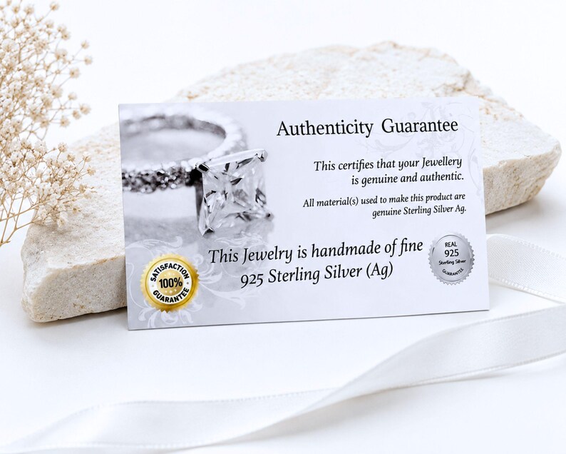 May include: A rectangular white authenticity guarantee card featuring a photograph of a silver ring with a square stone. The text reads Authenticity Guarantee, This certifies that your Jewellery is genuine and authentic, and 925 Sterling Silver.