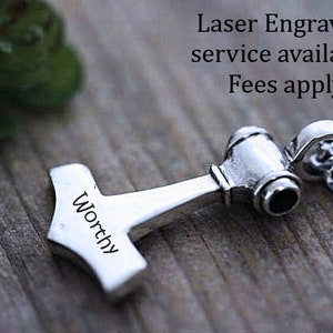 May include: A silver-toned metal pendant shaped like a hammer, featuring the word Worthy engraved on its side. The pendant is attached to a silver-toned chain. Text in the image reads: Laser Engraving service available. Fees apply.