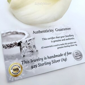 May include: A white card with the text "Authenticity Guarantee" and "This certifies that your Jewellery is genuine and authentic. All material(s) used to make this product are genuine Sterling Silver Ag. This Jewelry is handmade of fine 925 Sterling Silver (Ag)" printed on it. The card also has a small silver seal with the text "REAL 925 Sterling Silver Guarantee" printed on it.