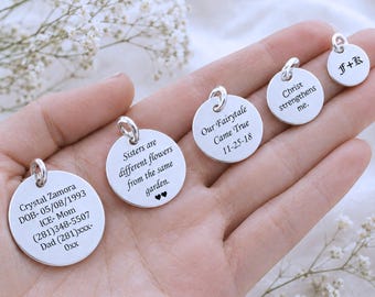 May include: Four circular silver charms with engraved text. The largest reads Crystal Zamora DOB- 05/08/1993 ICE- Mom (281)348-5507 Dad (281)xxx-0xx. Others read Sisters are different flowers from the same garden, Our Fairytale Came True 11-25-18, Christ strengthens me, and F+K.
