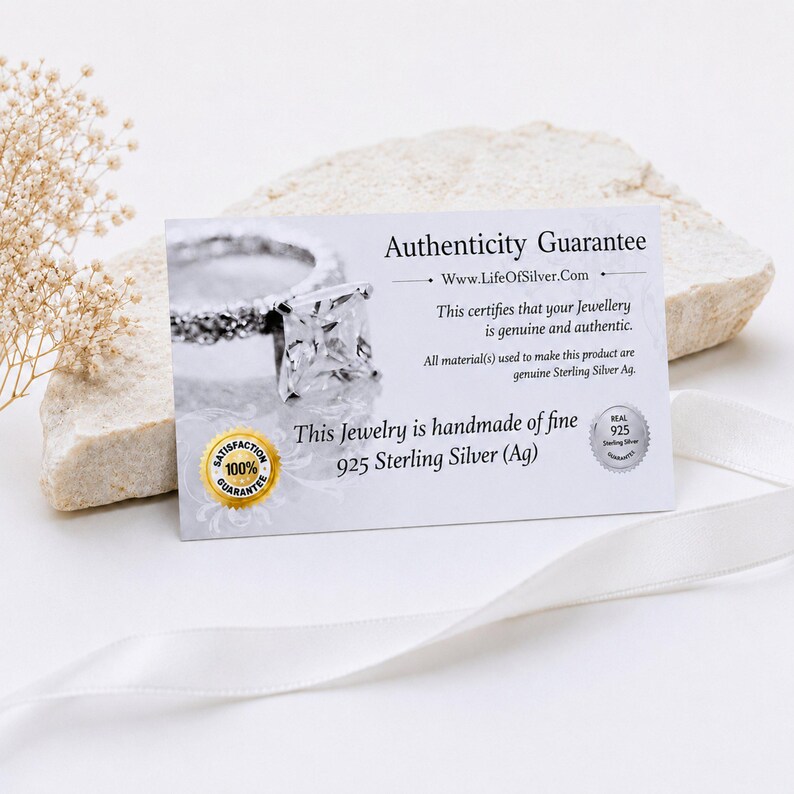 May include: A rectangular white authenticity guarantee card featuring a photograph of a silver ring with a square-cut stone. The text reads Authenticity Guarantee, www.LifeOfSilver.com, and This Jewelry is handmade of fine 925 Sterling Silver.