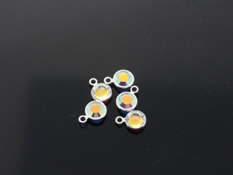 May include: Five silver-toned connector charms with iridescent rainbow-coloured glass stones. Each charm has a loop on the top and a small loop on the side.
