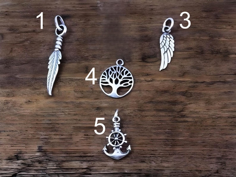 May include: Four silver-toned metal pendants labeled with numbers. Pendant 1 is a feather, pendant 3 is a wing, pendant 4 is a circular tree of life, and pendant 5 is a ship's wheel combined with an anchor. Each piece includes a small jump ring.