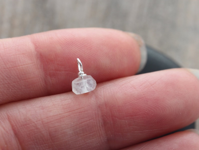 May include: A small, clear, faceted crystal charm with a silver wire loop. The charm is about the size of a 10 pence coin.