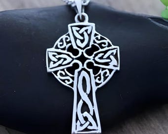 May include: A silver-toned metal Celtic cross pendant featuring intricate openwork knotwork patterns throughout the arms and center. The cross is suspended from a silver-toned chain, showcasing a detailed design with cutouts that create a complex, interlaced appearance across the entire surface of the pendant.