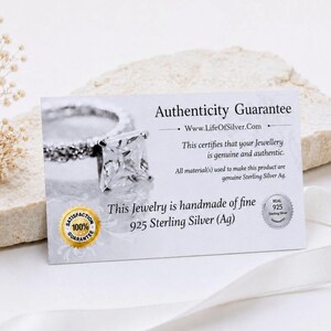 以下が含まれることがあります： 銀の指輪の画像と「Authenticity Guarantee, Www.LifeOfSilver.Com, This certifies that your Jewellery is genuine and authentic, 925 Sterling Silver (Ag)」というテキストが記載された白い長方形の真正性保証カード。