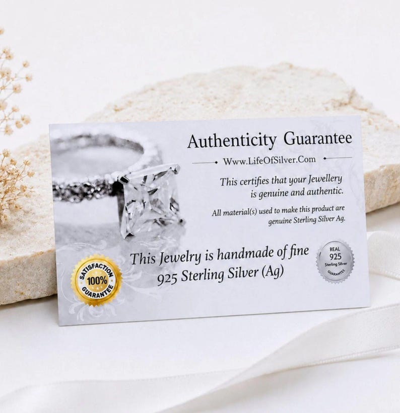 以下が含まれることがあります： 銀の指輪の画像と「Authenticity Guarantee, Www.LifeOfSilver.Com, This certifies that your Jewellery is genuine and authentic, 925 Sterling Silver (Ag)」というテキストが記載された白い長方形の真正性保証カード。
