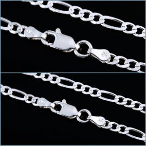 May include: A polished sterling silver Figaro chain necklace featuring a lobster claw clasp. The metal links are stamped with 925 and ITALY. The chain consists of a repeating pattern of three small circular links followed by one elongated oval link.
