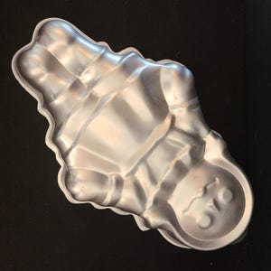 Puede incluir: Un molde para hornear de aluminio plateado con forma de esqueleto. El molde tiene detalles de costillas y cr&aacute;neo, perfecto para pasteles tem&aacute;ticos. Est&aacute; dise&ntilde;ado para crear un postre &uacute;nico y festivo.