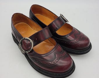 Zapatos John Fluevog Angela Mary Jane raros en piel color burdeos con efecto desgastado, hechos en Polonia.