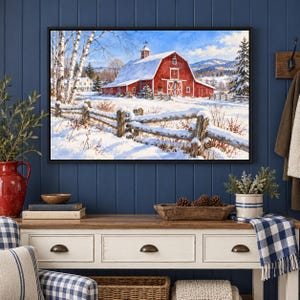 May include: A framed landscape print featuring a red barn covered in snow, situated in a winter field with a wooden fence in the foreground, birch trees to the left, and distant mountains under a clear blue sky.