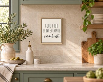 May include: A rectangular wall sign with a light wood frame and a white background featuring the black text: GOOD FOOD SLOW EVENINGS warm hearts. The sign is mounted on a beige tiled wall above a kitchen counter with various items.