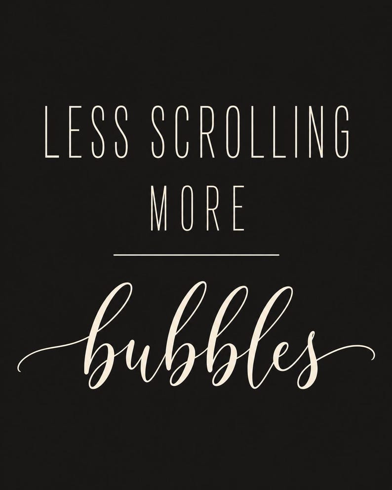 May include: A black rectangular sign featuring the white text LESS SCROLLING MORE in a clean sans-serif font, followed by a horizontal line and the word bubbles written in a white, elegant, flowing cursive script font.