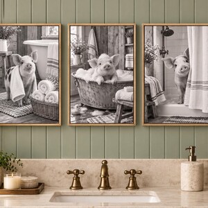 May include: A set of three framed black and white wall art prints featuring a piglet in a bathroom setting. The first shows a piglet with a towel, the second a piglet in a metal tub, and the third a piglet peeking from behind a shower curtain.