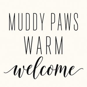 May include: A rectangular sign featuring the black text MUDDY PAWS WARM welcome printed on a solid off-white background. The words MUDDY PAWS and WARM are in a tall, thin, sans-serif font, while the word welcome is in a cursive script.
