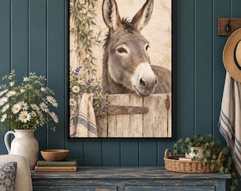 May include: A framed wall art print featuring a brown donkey peering over a weathered wooden fence. The scene includes a textured beige wall, green foliage, and a small cluster of white and purple flowers draped over the fence edge.