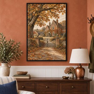 May include: A framed wall art print depicting a stone manor house behind a black metal gate, surrounded by large trees with orange and yellow autumn foliage. A gravel path covered in fallen leaves leads to the entrance of the building.