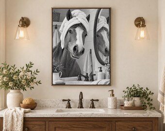 May include: A framed black and white wall art print depicting a horse wearing a white towel wrapped around its head like a turban, looking into a bathroom mirror. The horse is positioned in front of a sink with a faucet, soap dispenser, and small potted plant.