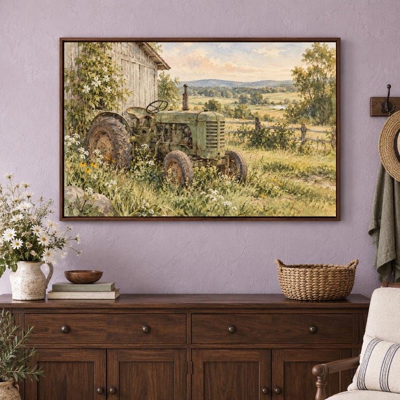 May include: A framed landscape painting depicting a weathered green tractor parked beside a rustic wooden barn in a grassy field filled with wildflowers, with rolling hills and a soft sky visible in the background of the rural scene.