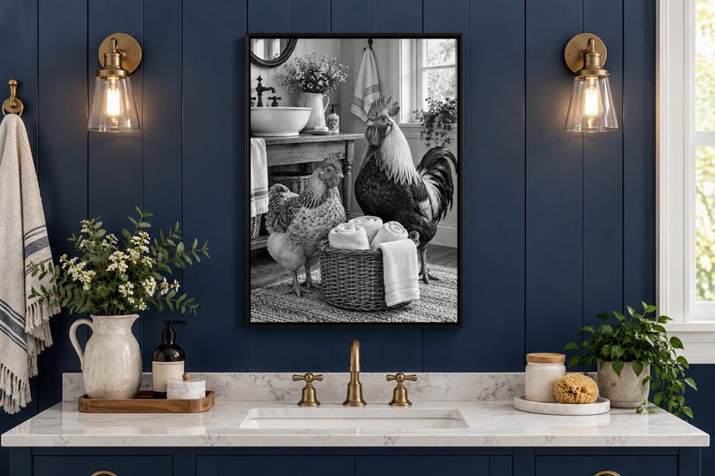 Op de afbeelding: Een rechthoekige wandkunstprint met zwarte lijst, voorzien van een zwart-witfoto van een haan en een kip naast een gevlochten mand vol witte handdoeken, geplaatst in een badkameromgeving met een wastafel en meubel.