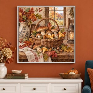 May include: A framed wall art print depicting a woven basket filled with various brown mushrooms, surrounded by autumn leaves and acorns on a wooden table. A ceramic pitcher, a lit lantern, and a plaid cloth are also visible in the scene.