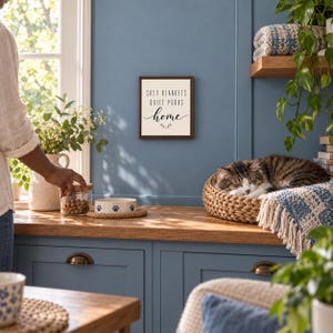 Może przedstawiać: Kwadratowy znak ścienny z ciemną drewnianą ramą i białym tłem, zawierający czarny napis "SOFT BLANKETS QUIET PURRS home" oraz małą dekoracyjną ikonę gałązki wyśrodkowaną pod tekstem na niebieskiej ścianie.