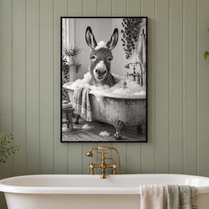 May include: A black and white framed wall art print depicting a donkey sitting in a clawfoot bathtub filled with soap bubbles. The donkey has foam on its head and ears, and a striped towel hangs over the side of the tub in the scene.