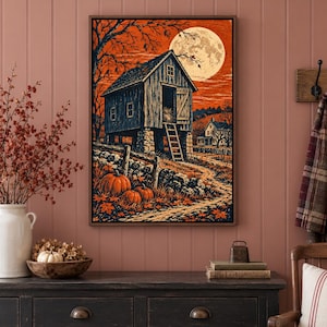 May include: A framed wall art print depicting a rustic wooden barn elevated on stone pillars, set against a vibrant orange sky with a large full moon. In the foreground, orange pumpkins rest on a path near a stone wall and bare trees.
