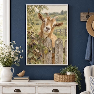 May include: A framed wall art print featuring a brown goat peering over a weathered wooden fence. The scene includes a blackberry bush with dark berries and white flowers in the foreground, set against a soft, muted green rural landscape.