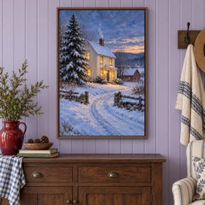 May include: A framed wall art print depicting a winter landscape with a two-story house, a snow-covered pine tree, and a stone fence along a path. The scene features warm glowing windows against a twilight sky with soft clouds and snow.