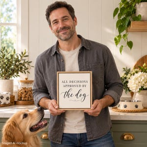 May include: A square wooden sign with a light background and black text that reads ALL DECISIONS APPROVED BY the dog. The sign features a simple serif font for the upper text and a decorative script font for the word the dog.