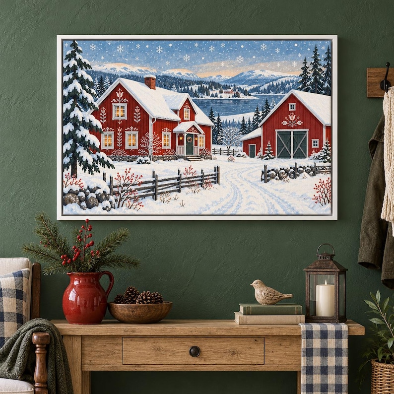 May include: A framed wall art print depicting a snowy winter landscape with two red houses, a wooden fence, and evergreen trees under a sky filled with falling snowflakes. The scene features a frozen lake and distant mountains in the background.