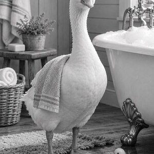 以下が含まれることがあります： バスルームに立つ白いガチョウ。背中には小さな灰色のタオルが掛けられています。ガチョウは泡で満たされた猫足のバスタブの近くにいて、床には小さな黄色いゴム製のアヒルが置かれています。