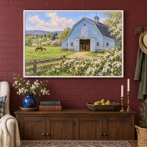 May include: A framed landscape painting depicting a light blue barn in a grassy field with a horse and foal. The scene includes a wooden fence, blooming white bushes, and distant hills under a bright blue sky with soft clouds.