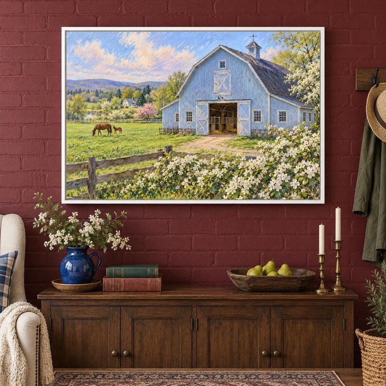 May include: A framed landscape painting depicting a light blue barn in a grassy field with a horse and foal. The scene includes a wooden fence, blooming white bushes, and distant hills under a bright blue sky with soft clouds.