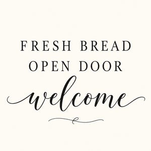 May include: A white rectangular sign featuring black text that reads FRESH BREAD OPEN DOOR welcome. The first two lines are in a simple serif font, while the word welcome is in a flowing script font with a decorative flourish underneath.