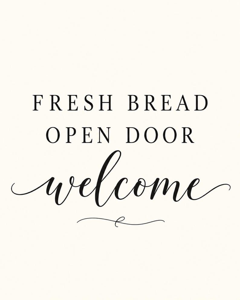 May include: A white rectangular sign featuring black text that reads FRESH BREAD OPEN DOOR welcome. The first two lines are in a simple serif font, while the word welcome is in a flowing script font with a decorative flourish underneath.