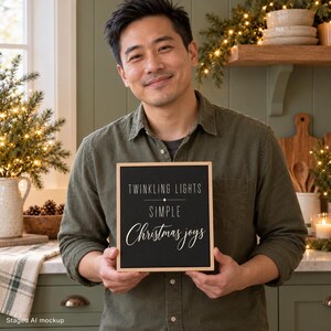May include: A square wooden-framed sign with a black background and white text that reads: TWINKLING LIGHTS, SIMPLE, Christmas joys. The sign features a small star icon between the first two lines and uses a mix of sans-serif and script fonts.