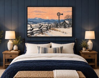 May include: A rectangular wall art print depicting a snowy rural landscape with a wooden fence, a windmill, and a small house under a soft orange sunset sky. The scene is framed in black and mounted on a dark blue vertical paneled wall above a bed.