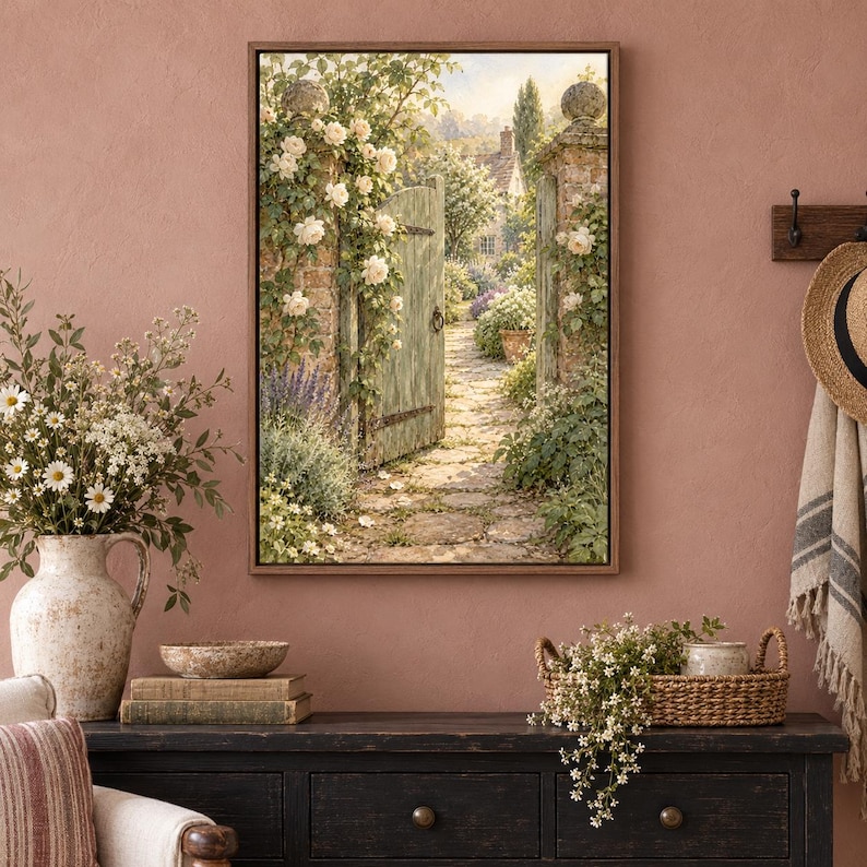 May include: A framed wall art print depicting a stone garden gate opening onto a sunlit cobblestone path, surrounded by climbing white roses and lush greenery. The scene features a rustic wooden gate, stone pillars, and a cottage in the distance.