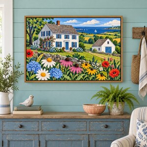 May include: A framed landscape painting depicting a white two-story house with blue shutters, a stone wall, and a garden filled with red poppies, white daisies, and blue hydrangeas, set against a backdrop of rolling green hills and the blue sea.