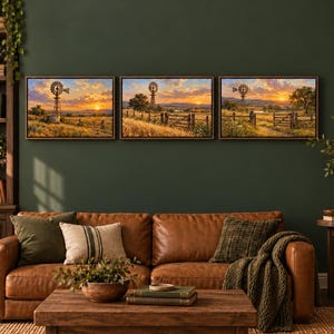 May include: A set of three rectangular wall art prints featuring a rural landscape with a windmill, golden fields, and a sunset sky. The artwork is displayed in dark frames and hung horizontally on a dark green wall above a leather sofa.