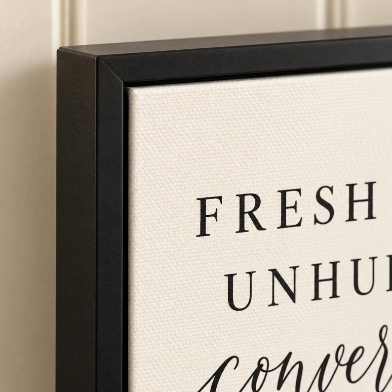 May include: A framed canvas wall art piece featuring a black matte frame and a cream-coloured textured canvas. The text printed in black ink reads FRESH, UNHURRIED, and the word conversation in a cursive script font is partially visible at the bottom.