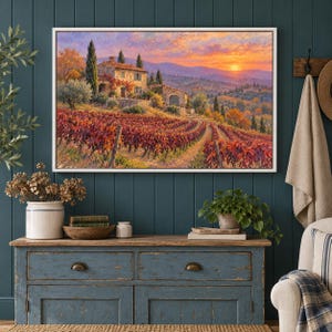 May include: A rectangular framed wall art print depicting a stone house nestled in a vineyard during sunset. The landscape features rows of red and orange grapevines, rolling hills, and a vibrant sky with hues of pink, orange, and yellow.
