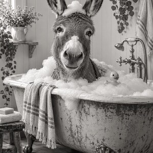 May include: A black and white image of a donkey sitting in a clawfoot bathtub filled with soap bubbles. The donkey has foam on its head and nose. A small yellow rubber duck floats in the bubbles next to the donkey. A striped towel hangs over the edge of the tub.