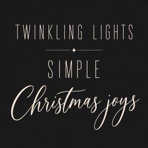 May include: A black rectangular sign featuring the light pink text TWINKLING LIGHTS in a clean sans-serif font, followed by a small star icon, the word SIMPLE, and the cursive script text Christmas joys in a light pink color.