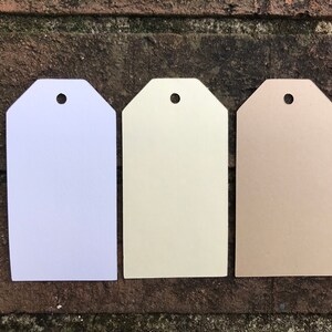 May include: Three blank gift tags with a hole punched at the top. The tags are white, cream, and brown.