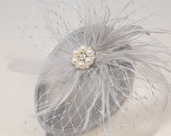 Shimmering silver teardrop shape fascinator with rhinestone and pearl brooch.