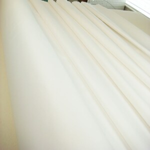 May include: A close-up of a white fabric, folded in a series of parallel lines, creating a smooth, even surface.