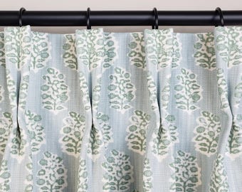 May include: Light blue and white patterned curtains with a floral design. The curtains are hanging from a black rod with black rings. The fabric has a textured appearance.